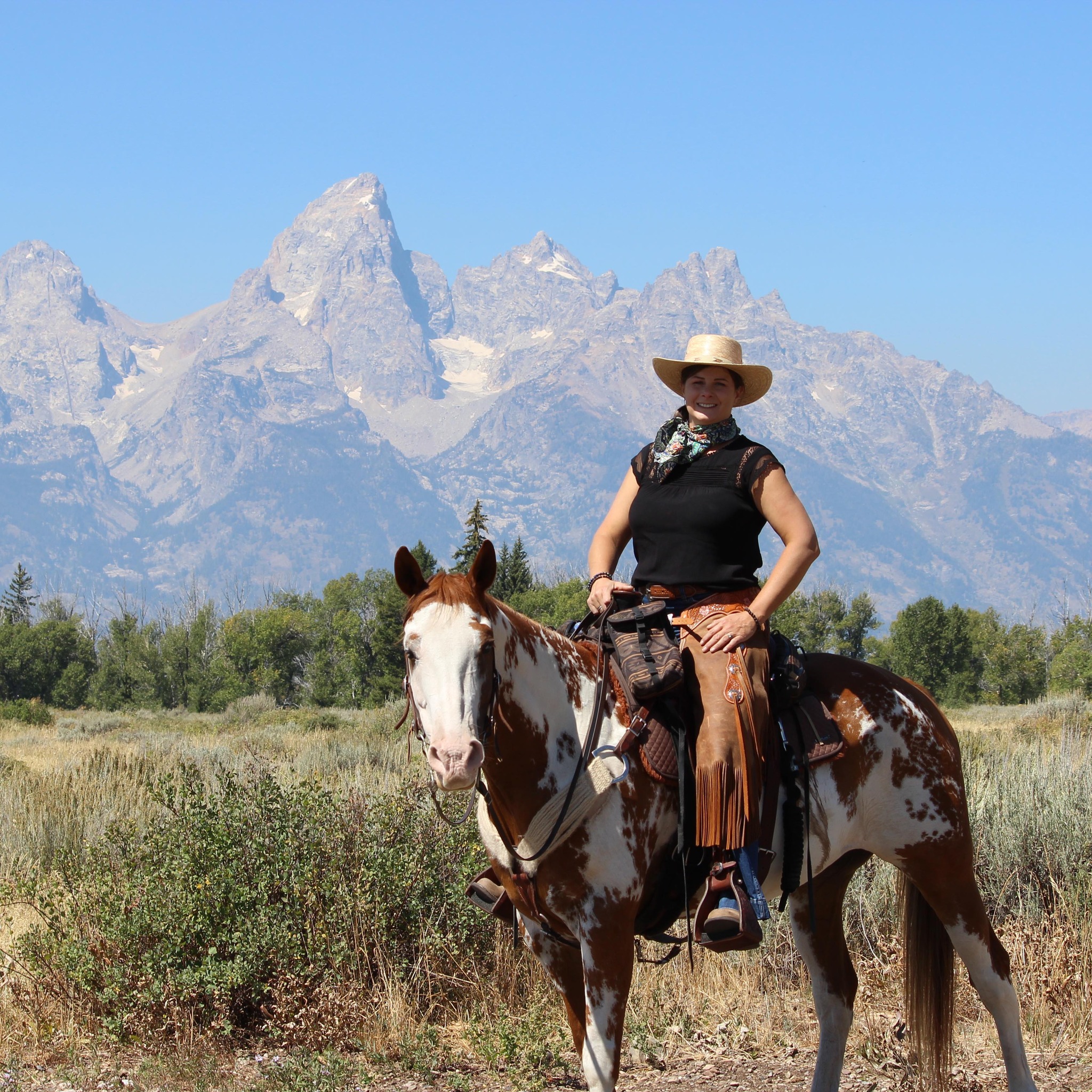 Bree riding beneath dramatic mountain peaks