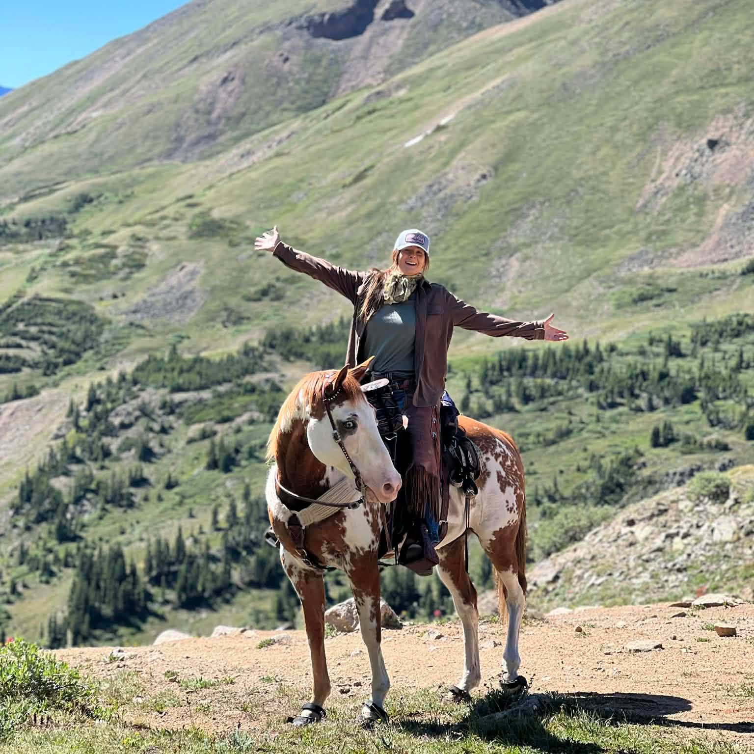 Bree celebrating from horseback high in the mountains