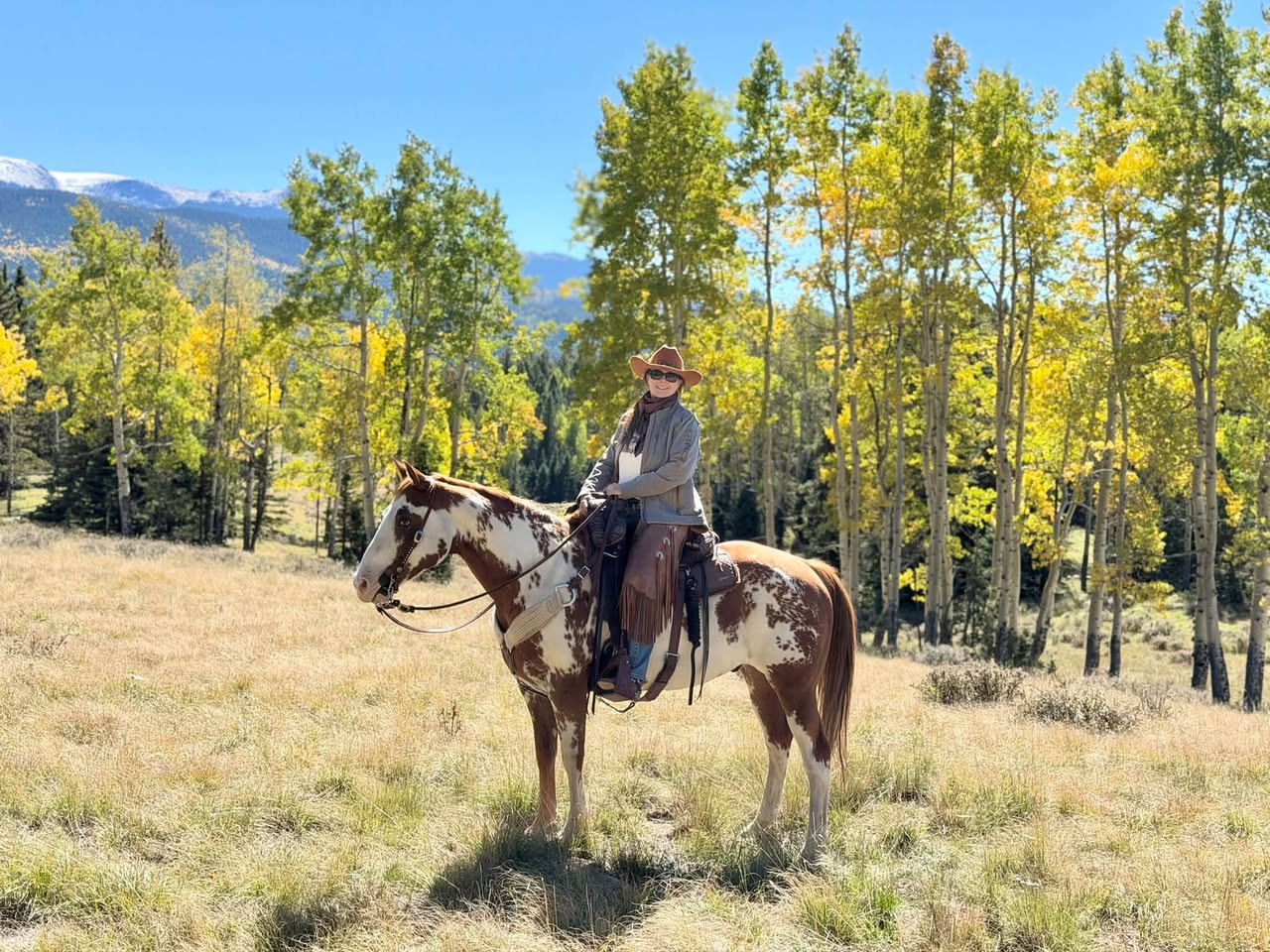 Bree and her paint horse in a meadow framed by golden aspens